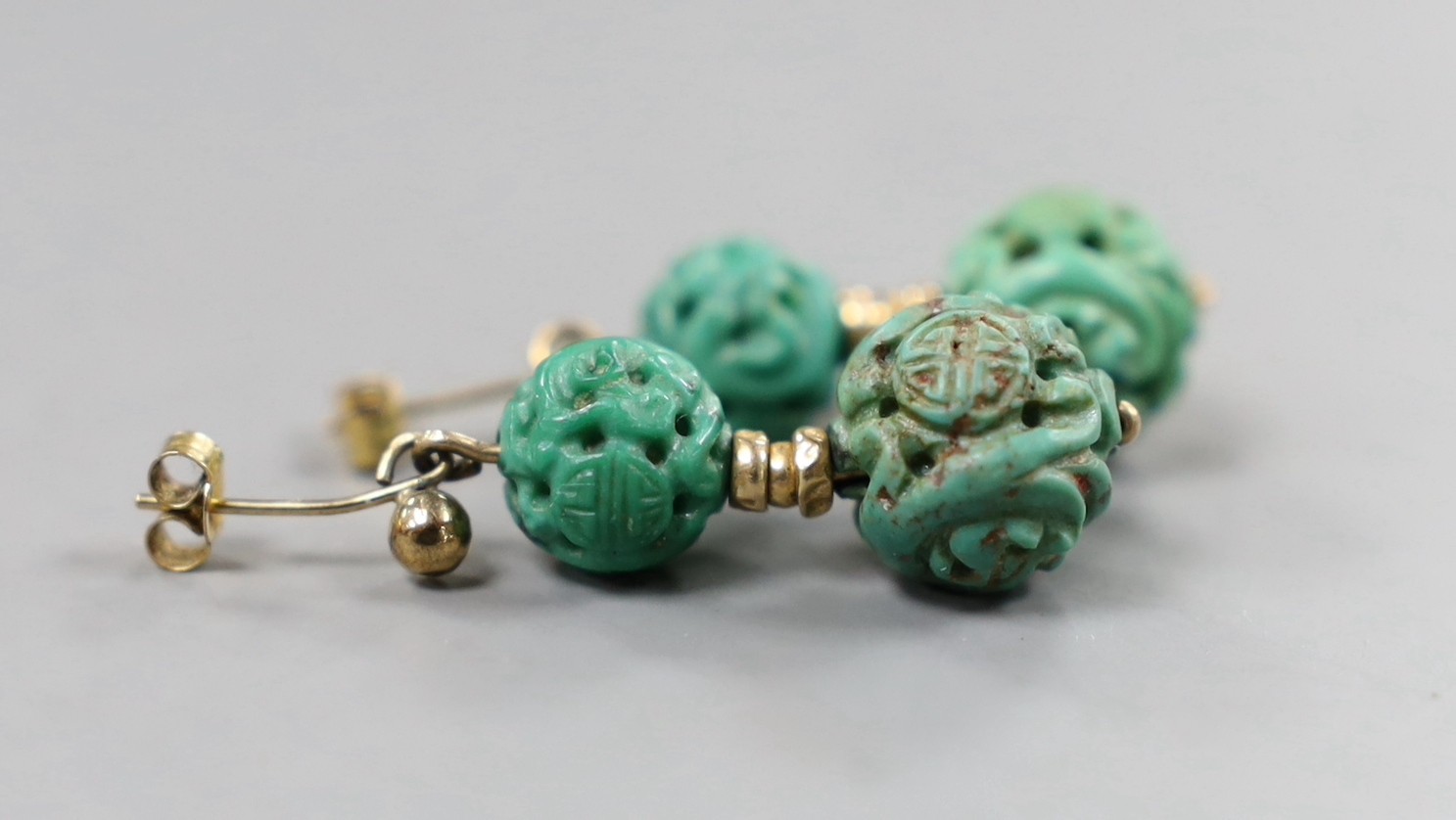 A pair of Chinese yellow metal and two turquoise bead set earrings, both carved with Shou medallions, 25mm, gross weight 5.2 grams.